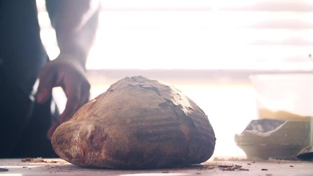Closeup of a man cutting a new baked bread in half