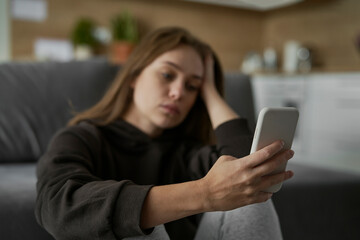 Caucasian nervous woman looking at mobile phone with sad face