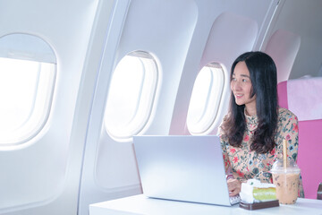 Fototapeta premium Asian young Businesswoman working using laptop compuer sitting near windows at first class on airplane during flight,Traveling and Business concept