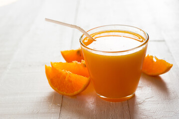 Fresh orange juice in the glass with orange fruit on white wood