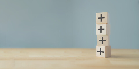 Plus sign in wooden cubes stacking. Positive things; additional, added value, benefits, improve,...
