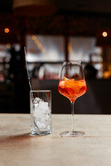 Glass with aperol cocktail and ice on bar counter