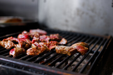 Pieces of bbq meat on grill grate in restaurant