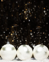 Christmas banner decorations view of three silver evening balls with white snow on it on dark background with silver colors bokeh and artificial snow. Holidays concept with copy space