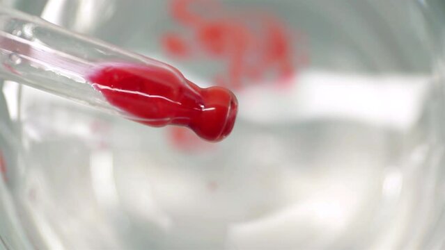 A drop of red dye falling from a pipette