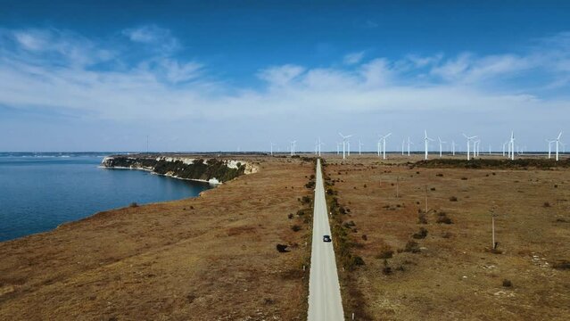 drone filming car driving on a road in Bulgaria along Cape Kalikra and numerous wind turbines