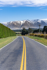 Landscape of Canterbury, South Island New Zealand, taken on the Inland Scenic Route 72, with wild bushes and snow-covered Alps in the background.