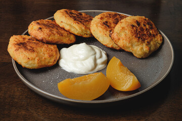 Cottage cheese pancakes,curd fritters with  and apricot slices  and sour cream in a dish. Gourmet Breakfast

