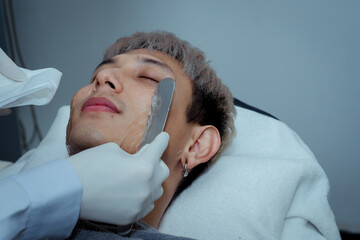 Beautician applying hydro gel mask on the young man face, before laser treatment in beauty salon....