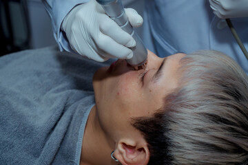 RF lifting procedure on the face of a young man in a spa salon. Radiofrequency lifting to correct the shape of a young man's face. ,Beauty clinic concepts.