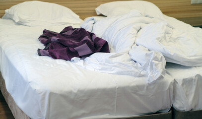 Bed with pillows and crumpled blanket. Crumpled blanket and pillows on empty rumpled bed in hotel room after sleeping in night