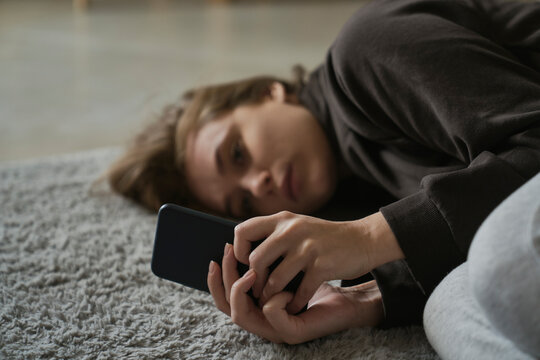 Caucasian nervous woman lying down on the floor with mobile phone