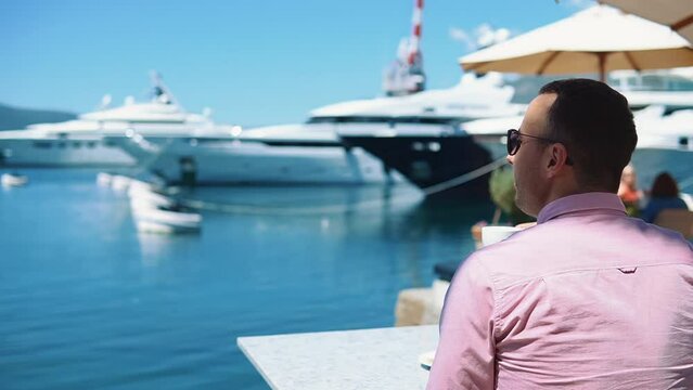 Successful man drinking coffee overlooking the yachts
