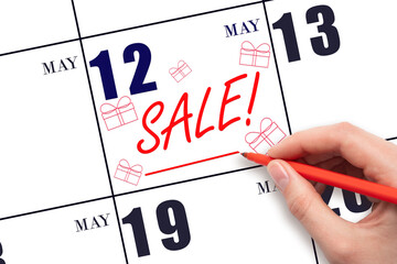 Hand writing text SALE and drawing gift boxes on calendar date May 12. Shopping Reminder