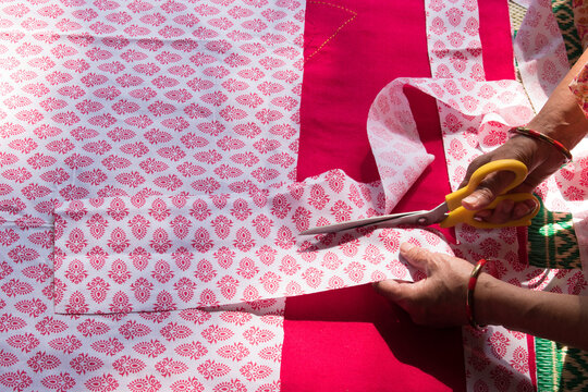 Closeup of a woman's hands cutting cloth with scissors for applique work in baby’s quilt or bed sheet. Concept of self employment woman and Female entrepreneurs in India.
