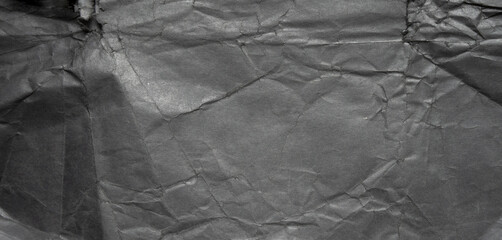 Rectangular texture of black paper. Background of dark photo paper with crumpled edges. Black background in the form of a banner.