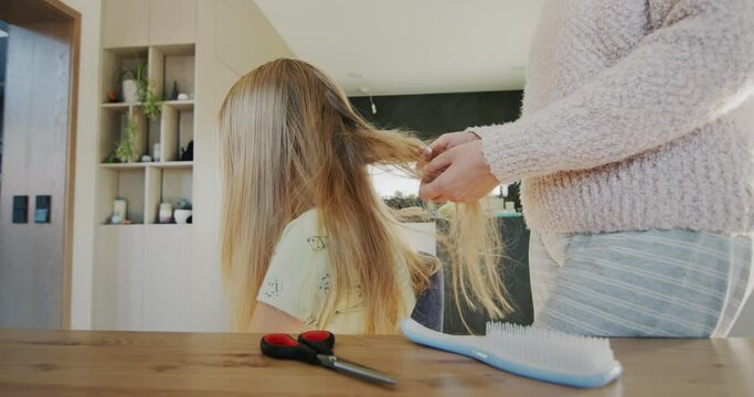 Mom untangles her daughter's long hair. Hair is very tangled and hard to comb