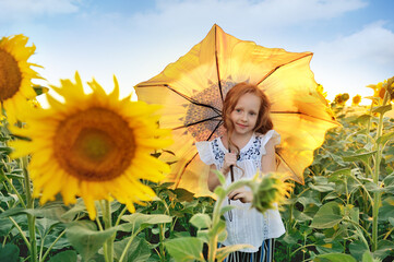 Girl at the sunflowers field under the umbrella with sunflower print