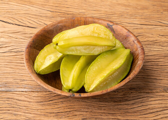 Starfruits in a bowl over wooden table