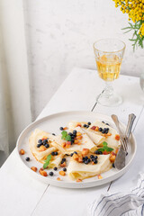 Pancakes with blueberries, peach and mint on a plate. White wooden table. Light background. Serving a rustic table with yellow flowers and a yellow drink