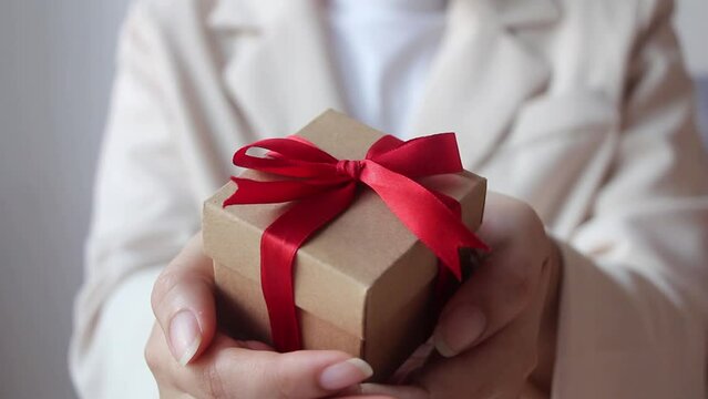 Woman hand holding gift box with red ribbon on white  background.