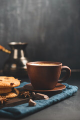 Crispy oatmeal cookies with raisins, coffee cup and turkish coffee pot, chocolate chunks on a dark background