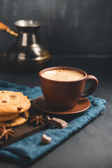 Crispy oatmeal cookies with raisins, coffee cup and turkish coffee pot, chocolate chunks on a dark background