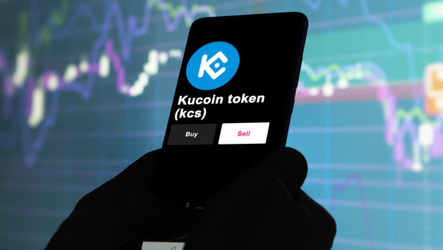 September 13th 2022, London UK. An investor's analyzing the kucoin token (kcs) coin on screen. A phone shows the crypto's prices to invest