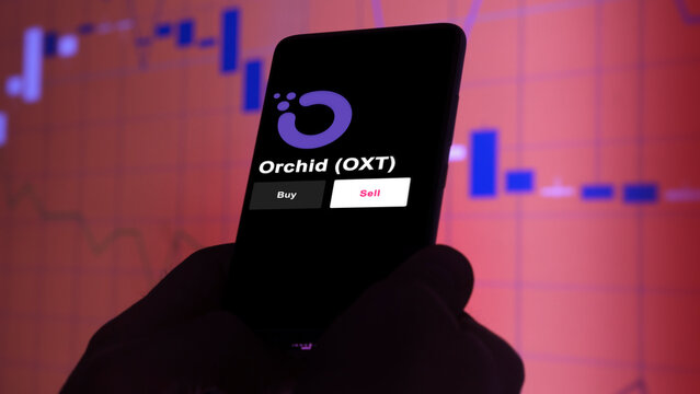 September 13th 2022, London UK. An investor's analyzing the Orchid (OXT) coin on screen. A phone shows the crypto's prices to invest