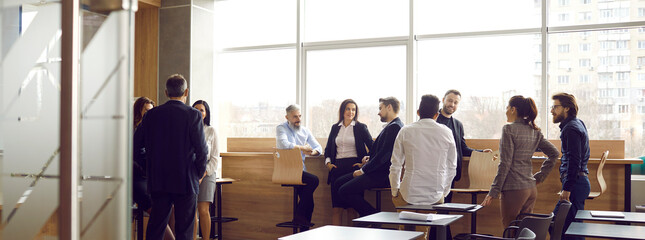 Office workers talk amicably and casually to each other during break at coworking center. Variety...