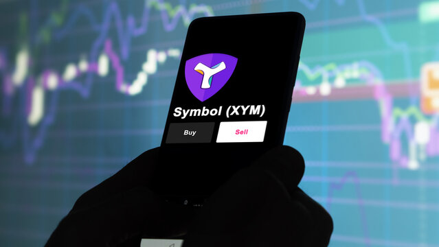 September 13th 2022, London UK. An investor's analyzing the Symbol (XYM) coin on screen. A phone shows the ETF's prices to invest