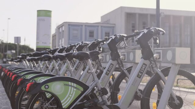 Many public bicycles for rent at bike station on street of Lisbon. Popular rental ecological transport for traveling around city for tourists and citizens. Portugal, Lisboa. July 16, 2022.