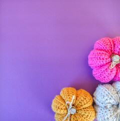yellow, beige and pink crochet pumpkin on purple ground with space for text
