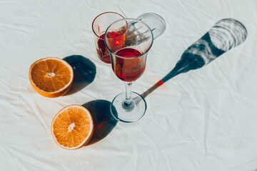 Red drink in a glass with oranges and flowers on the table