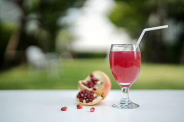 Pomegranate juice with fresh fruit on white wooden table.