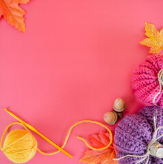handmade crochet pumpkin with autumn leaves on red ground with space for text, crochet hook and woolen ball