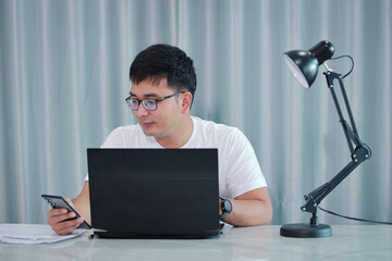 technology, remote job and lifestyle concept - happy asian man  man in glasses with laptop computer working at home office or online shopping, home work, freelance, online learning, studying.