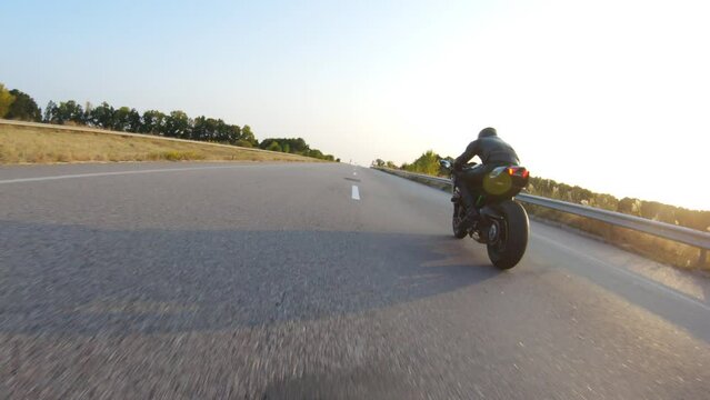 Follow to biker riding on modern sport motorbike at highway during sunny autumn day. Motorcyclist racing his motorcycle on country road. Guy drive bike during trip. Concept of journey. Aerial shot