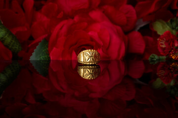 gold ring on red rose background.