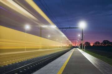 Modern railway at beautiful dawn. Light trail of high speed train on railroad track. Moving modern...