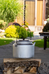 Iron tea kettle ready to be warmed up on a fire outdoor. Alternative way to supple cooking without gas and electricity 