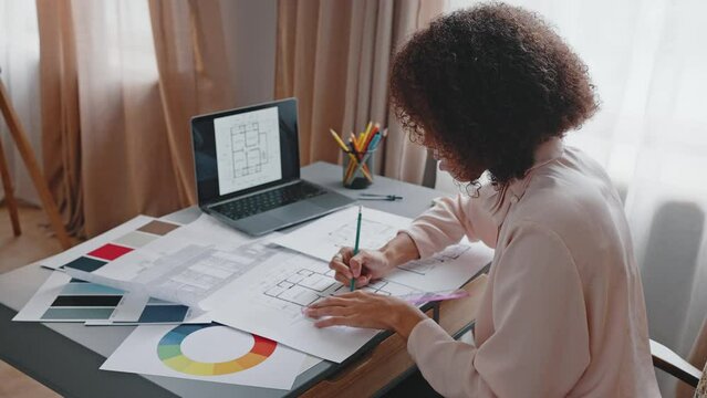 African American woman draws apartment layout at home