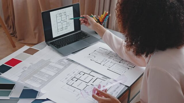 Black woman compares house apartment layout on laptop
