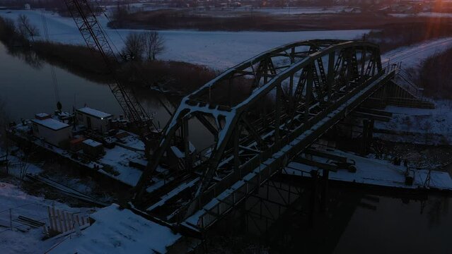 Above view, dolly move upwards, on vessel, barge, with large crane and two containers offices, docked at river coast for railroad bridge reconstruction, white of snow, frosty in the wintertime.  