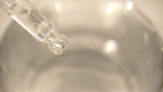 Drop of liquid drop from pipette into water