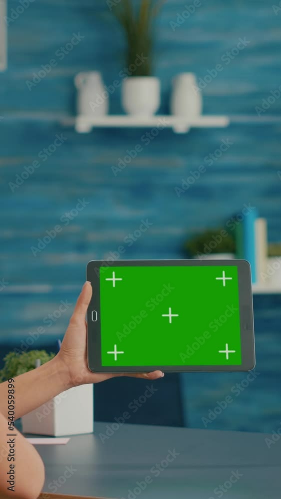Poster vertical video: woman looking at tablet computer with mock up green screen chroma key display browsi