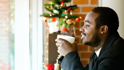 African businessman in a suit is happily drinking coffee during Christmas and New Year's Eve