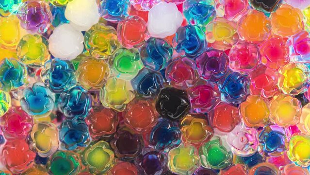 4K Time Lapse of Water beads growing in water close-up, abstract background. Texture of Hydrogel jelly balls - many colorful orbeez.