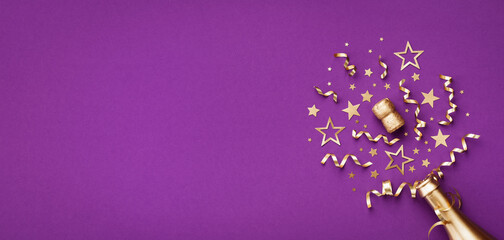 Golden champagne bottle with confetti stars and party decorations on purple background. Christmas, birthday or New Year card.
