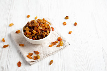 Organic Dried Raisins in a White Bowl, side view. Copy space.
